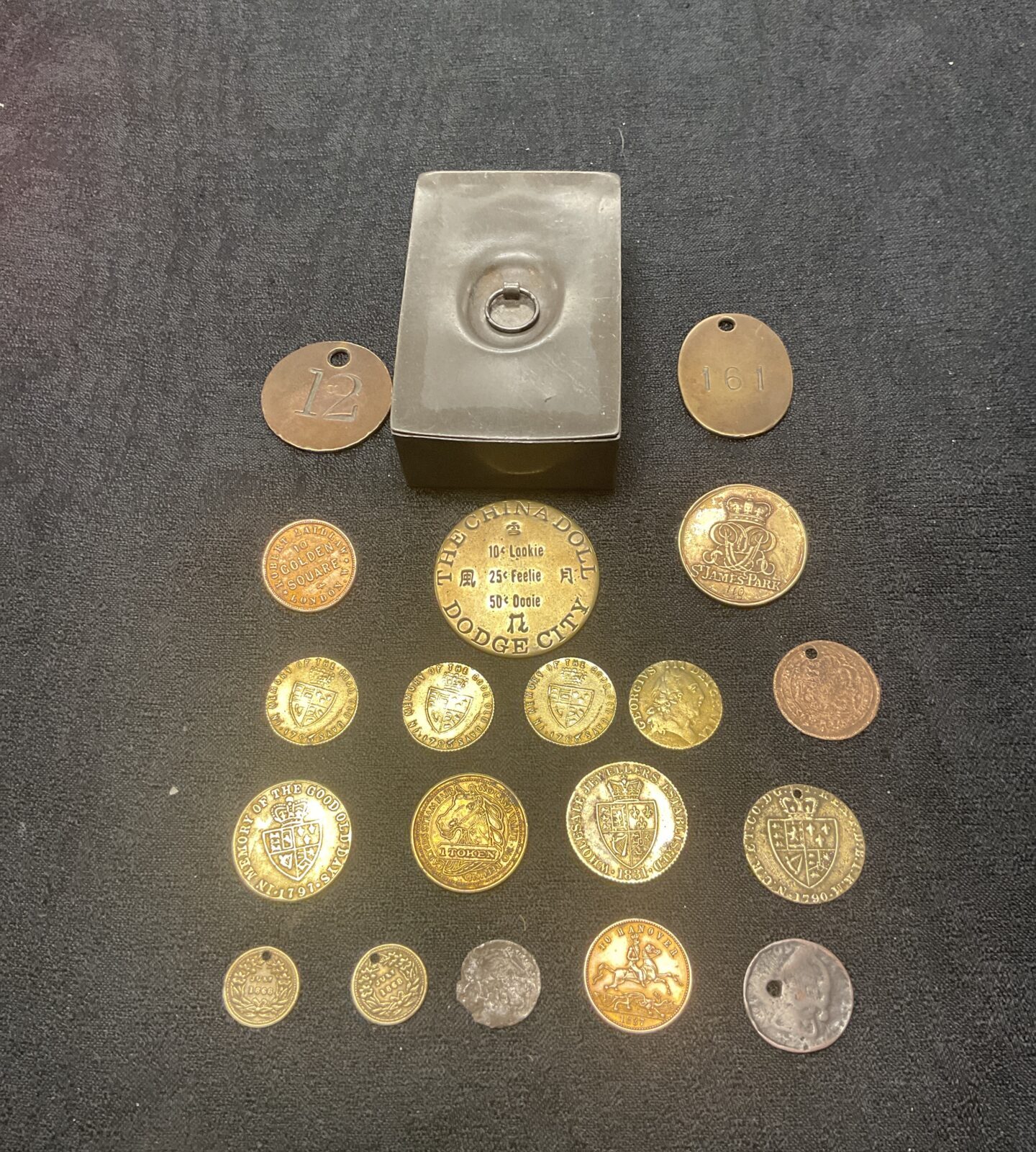 Antique pewter box with a collection of gaming tokens /coins Inc dodge city the china doll token and Cumberland jack token