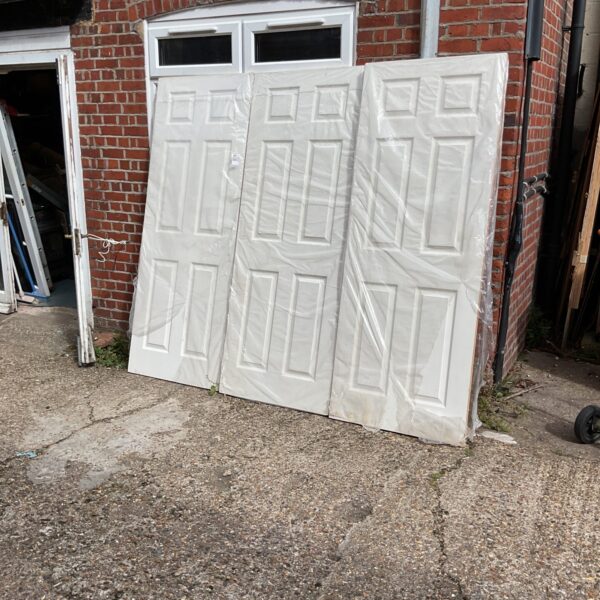 Set of three new white interior doors wrapped in plastic.