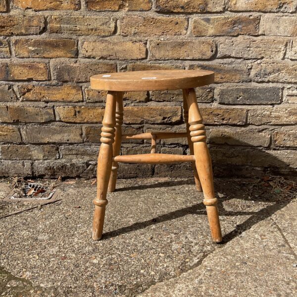Vintage pine stool with three legs, rustic farmhouse style.