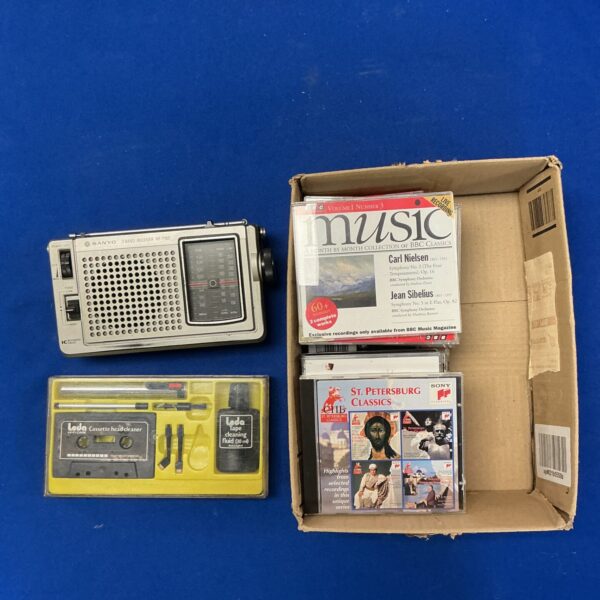 Vintage Sanyo receiver with classical CDs and tape care kit.