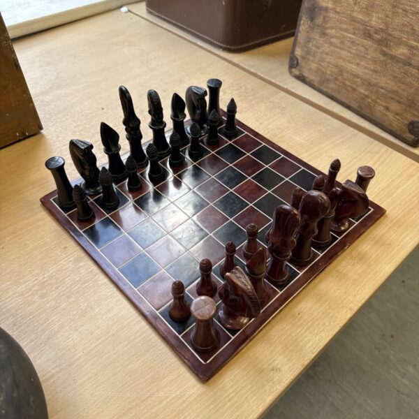 Vintage soapstone chess set on porcelain board, detailed carved pieces.