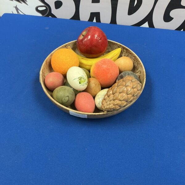 Colourful bowl of artificial fruit and eggs for kitchen display.