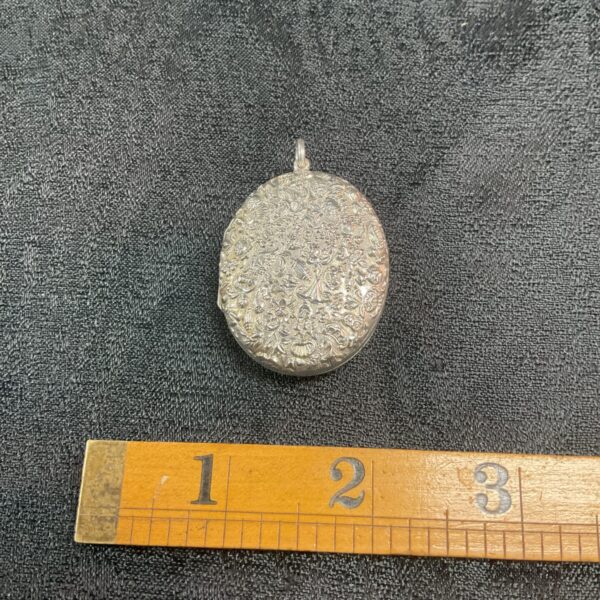 Antique whitemetal locket with floral repousse design.
