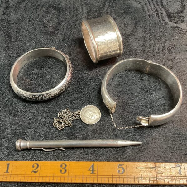 two silver bracelets knapkin ring pencil and chain and a coin