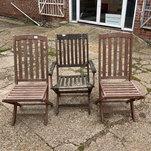 Set of three vintage wooden folding chairs in a garden setting.