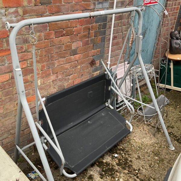 Black metal garden swing for outdoor use in a garden setting.