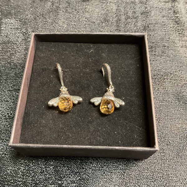 Close-up of vintage silver honeybee drop earrings with amber stones.
