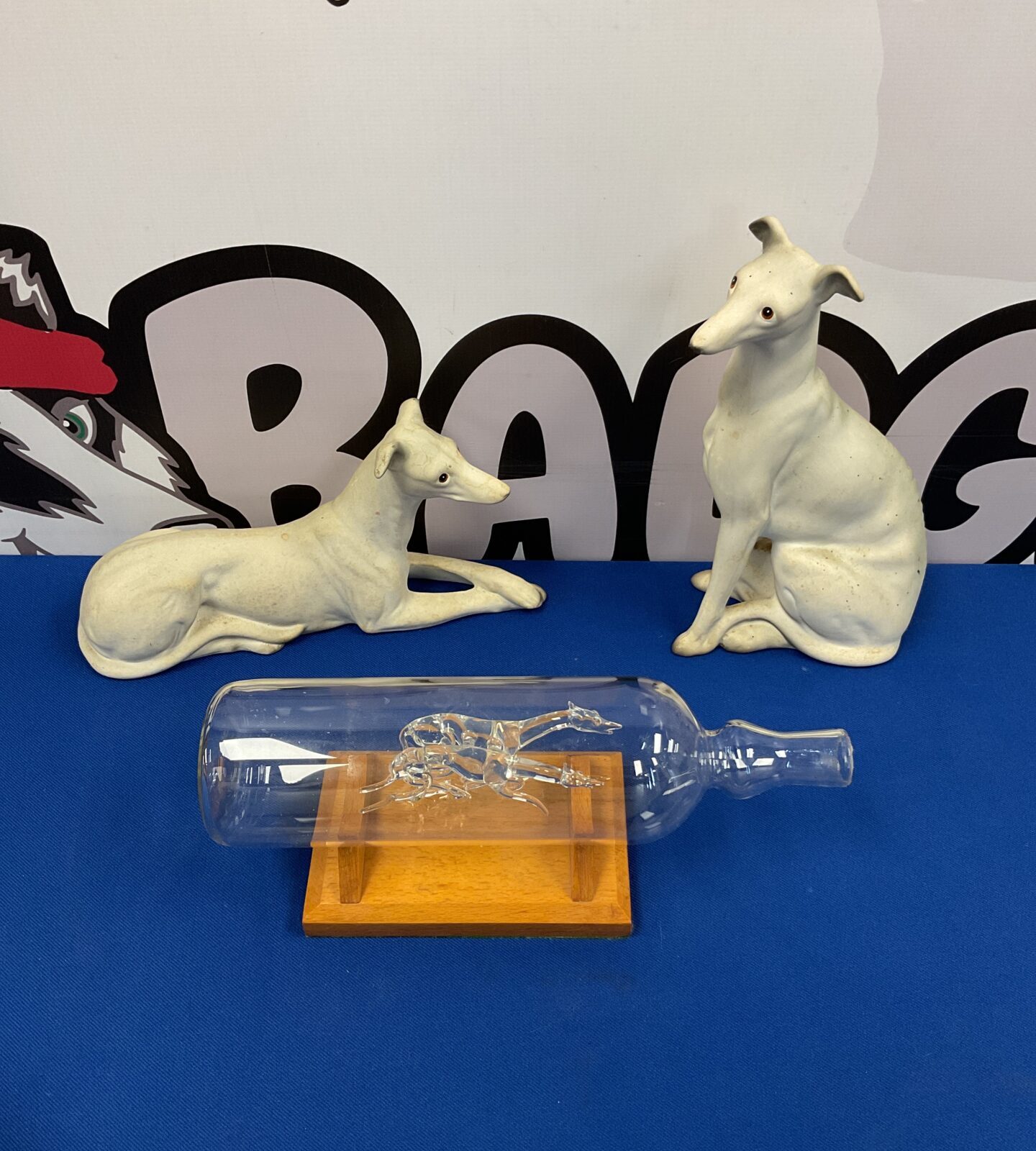 Two bisque porcelain greyhounds & racing greyhounds in a glass bottle
