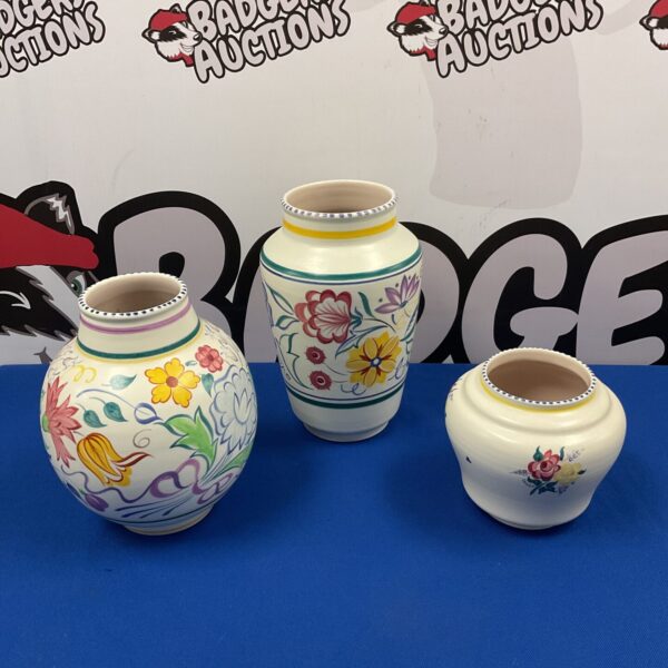 Three vintage Poole Pottery vases with floral designs.