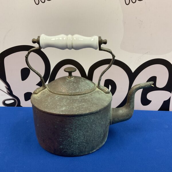 Antique copper kettle with ceramic handle, side view.