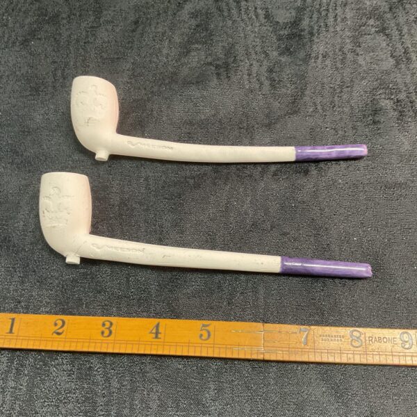 Pair of vintage Meeson clay pipes displayed on a dark surface.