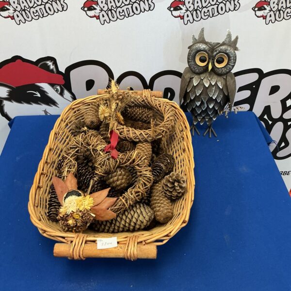 Rustic pine cone basket with metal owl figurine for home decor.