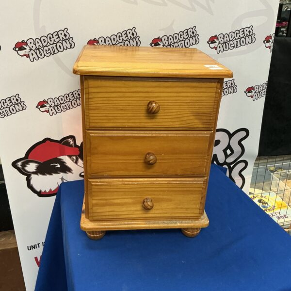 Vintage pine three-drawer bedside cabinet with warm wood tone.