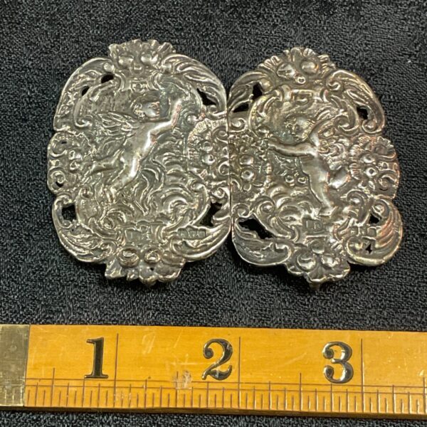 Antique Victorian silver nurses belt buckle with cherubic design.