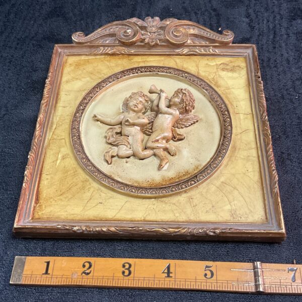 Vintage cherub wall plaque with gilded details.