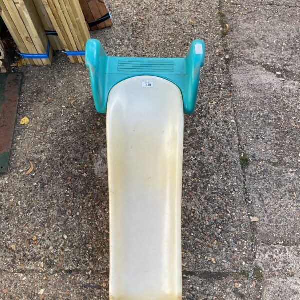 Bright blue Little Tikes plastic slide for toddlers in a garden setting.