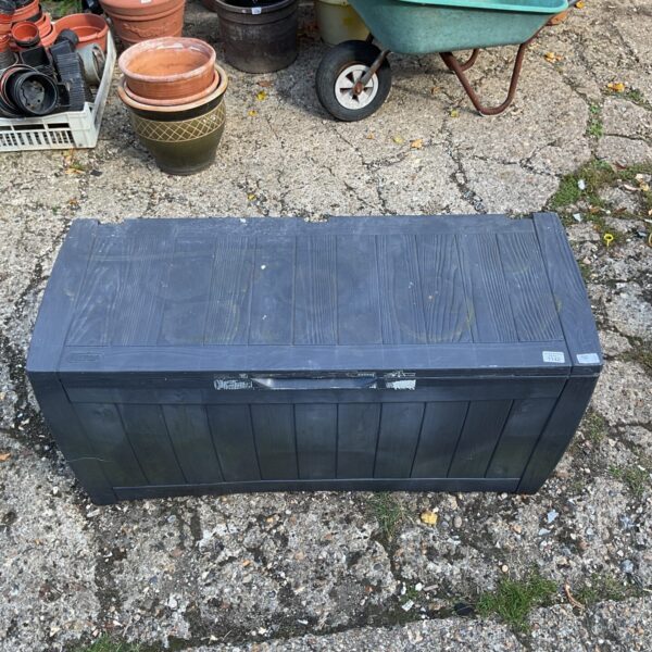 Dark grey plastic garden storage box in a garden setting.