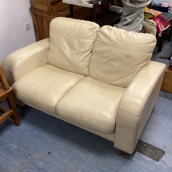 Cream leather two-seater sofa in a living room setting.