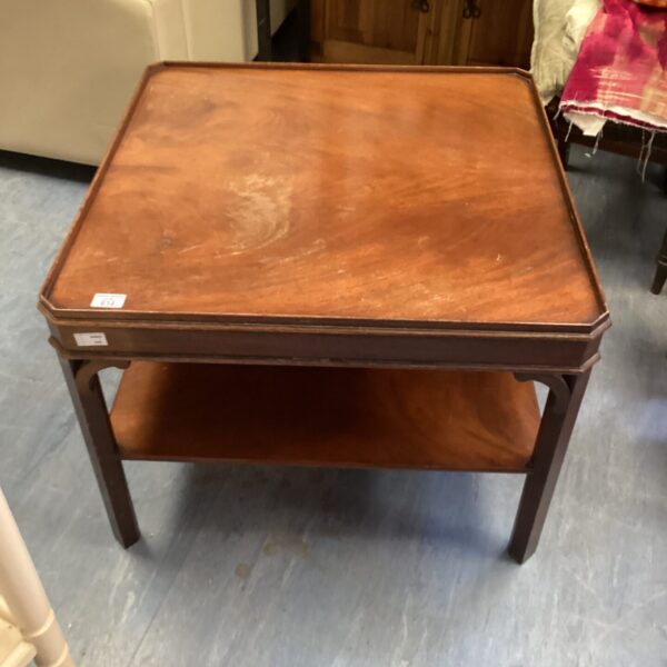 Vintage mahogany coffee table with lower shelf in a home setting.