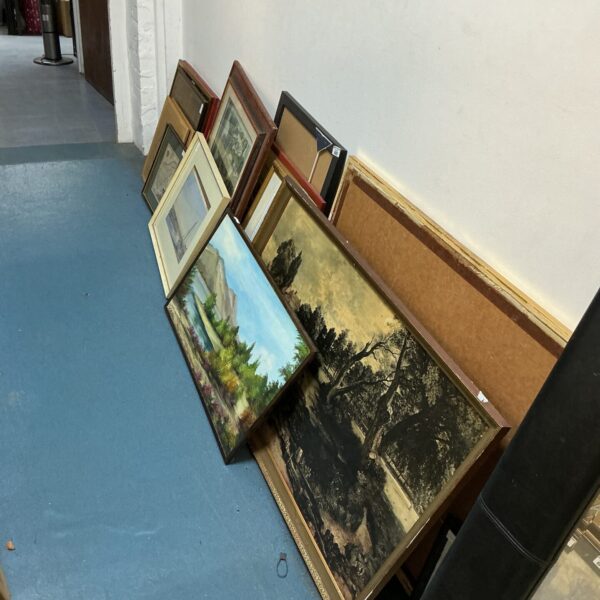 Mixed lot of vintage framed artworks and paintings on display.