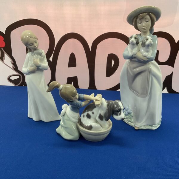 Lladro and Nao porcelain figurines depicting girls with dogs.