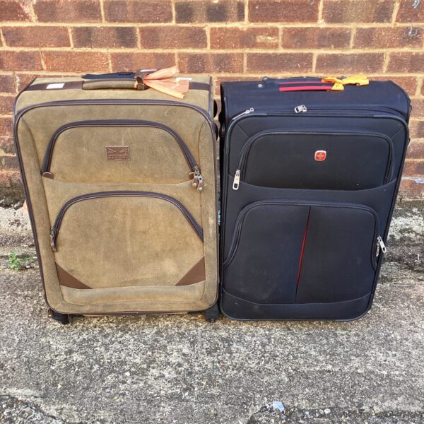 Two vintage suitcases, one tan and one dark, with wheels.