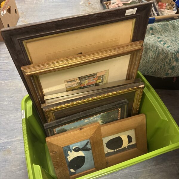 Stack of vintage picture frames with prints, antique wall decor.