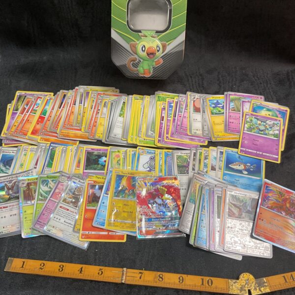 Large tin filled with a diverse Pokemon card collection.