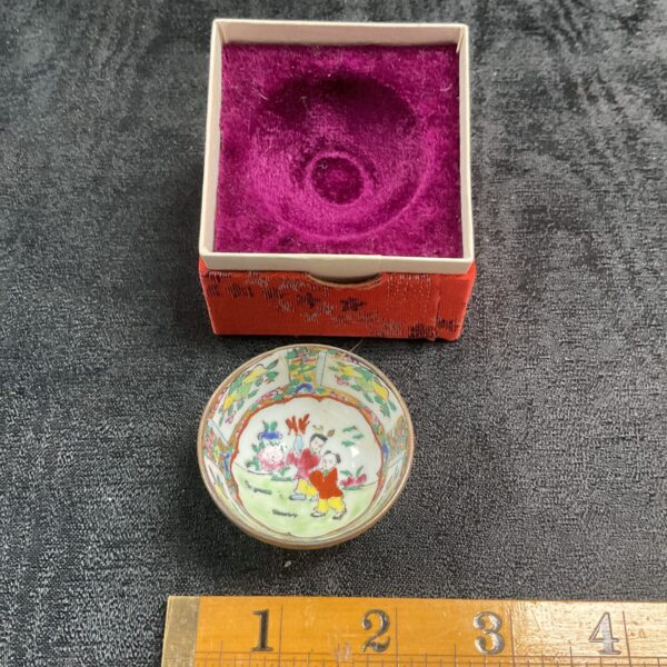 Antique Famille Rose tea bowl with figures in a garden scene.