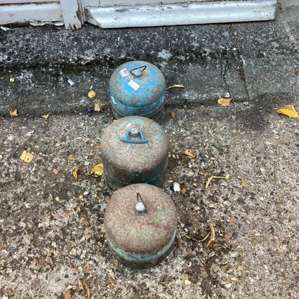 Three empty gas bottles showing signs of wear and rust.