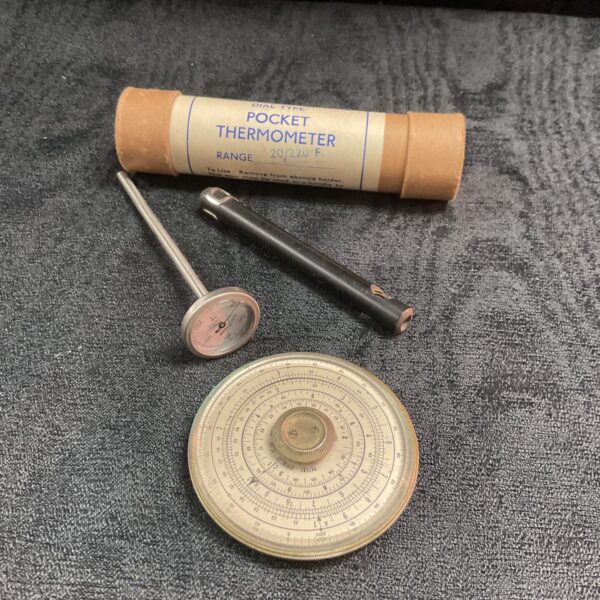 Vintage pocket thermometer and circular slide rule, antique scientific instruments.