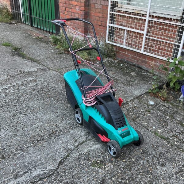 Green and grey Bosch electric lawnmower in a garden setting.
