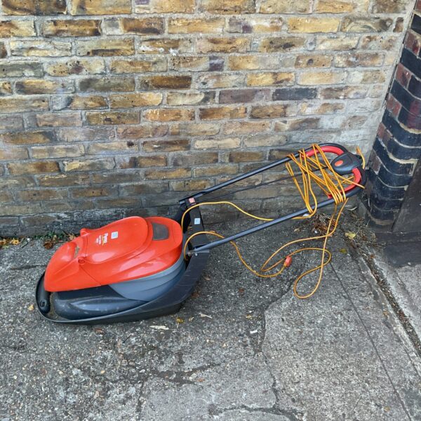 Red Flymo Easi Glide 300V electric lawnmower for garden maintenance.