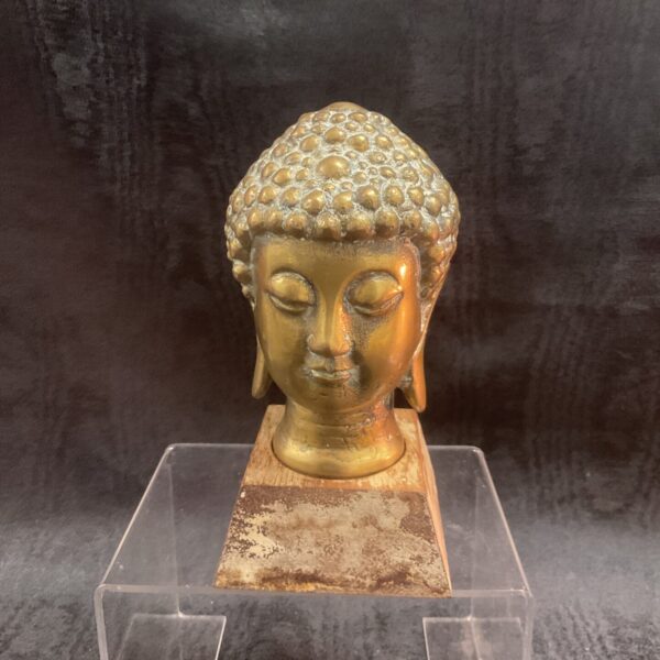 Vintage brass Buddha head on wooden base, serene Asian decor.