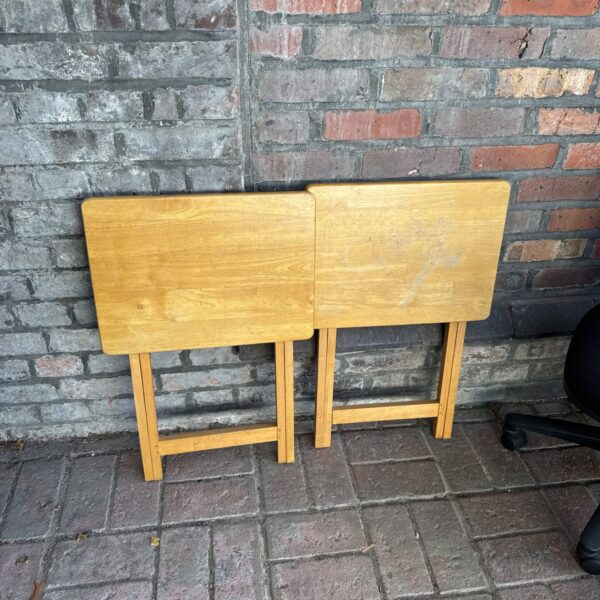 Two small wooden folding tables, side view.