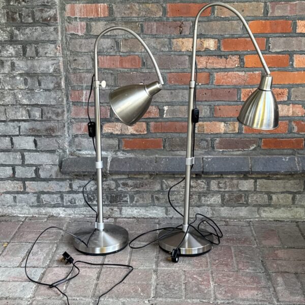 Pair of brushed steel floor lamps with adjustable heads.