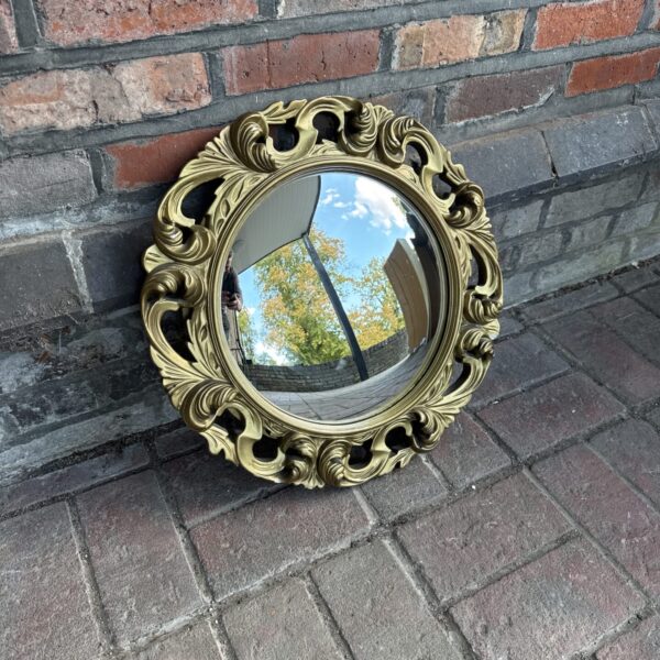 Vintage gilt porthole mirror with decorative frame.
