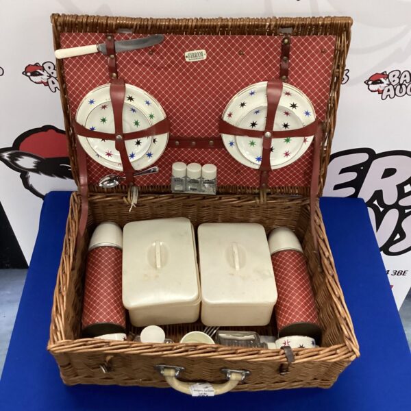 Vintage Sirram picnic basket with colourful tableware inside.