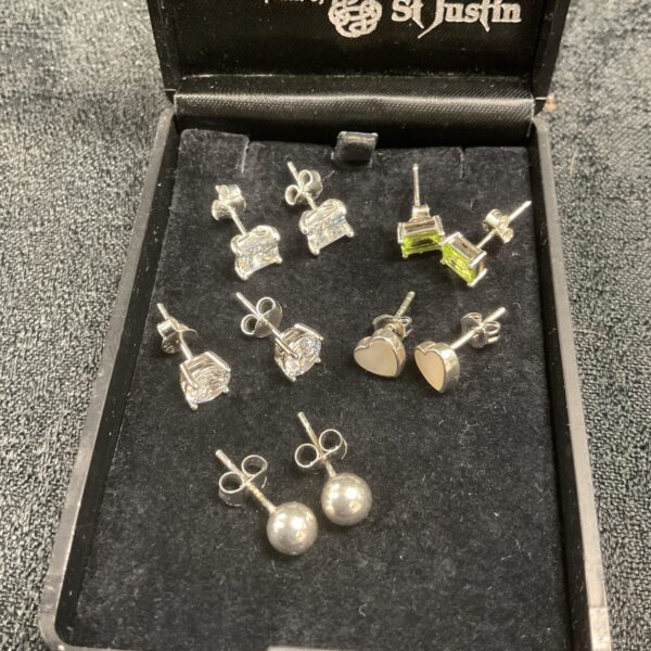 Close-up of five pairs of 925 silver stud earrings on a display card.