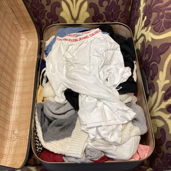 Vintage suitcase filled with a mixed lot of clothing items.