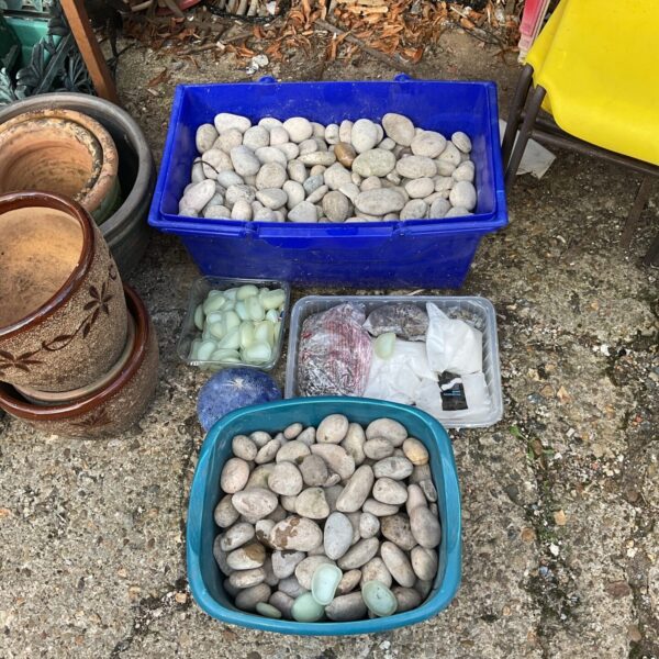 Large lot of mixed garden pebbles and stones in a blue container.