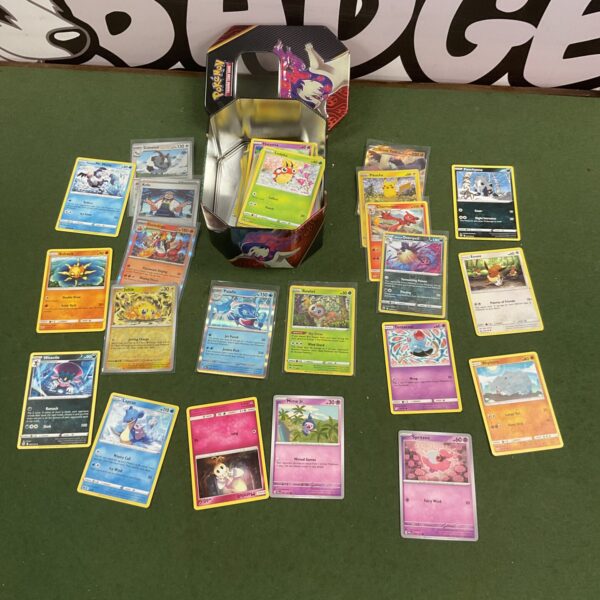 Assorted Pokemon cards inside a metal tin.