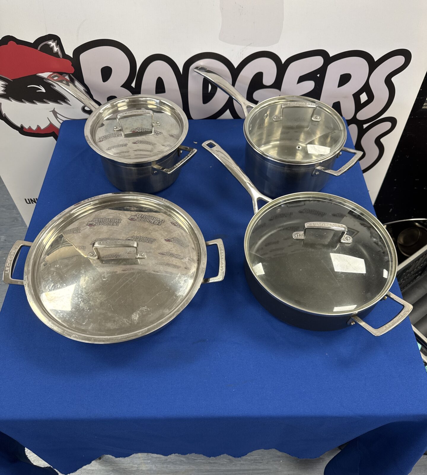 Four Le Creuset stainless steel cooking pans (one pan has incorrect lid)