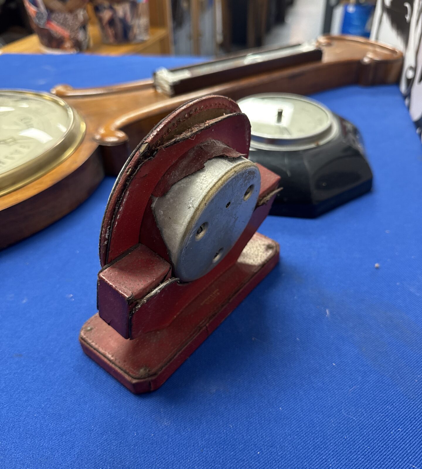 Close-up of a red vintage barometer showing leather separation.