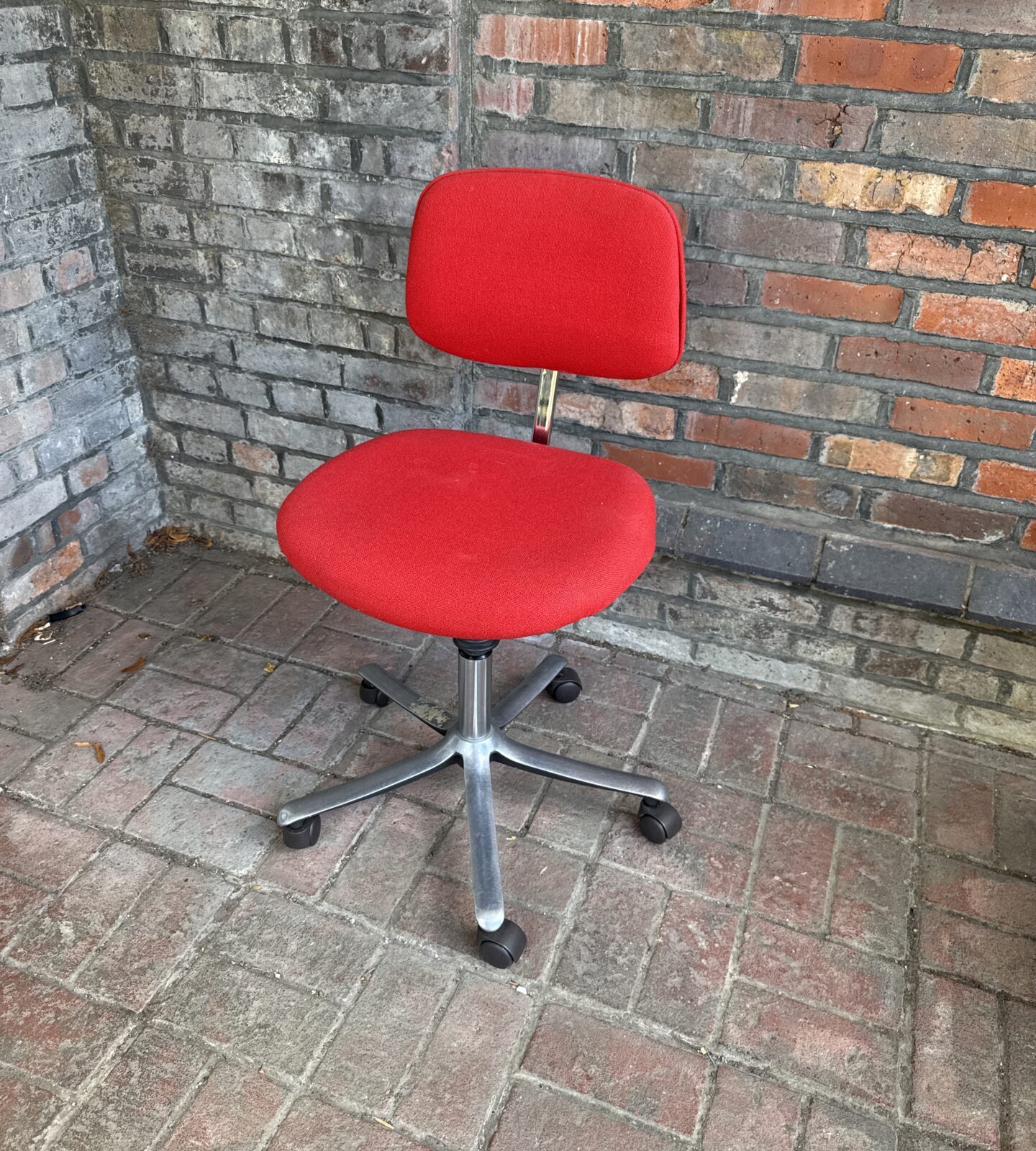Vintage red office chair with swivel base and casters.