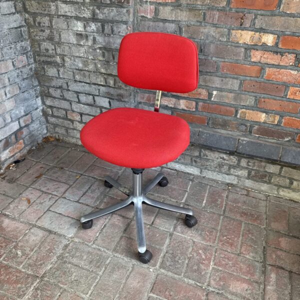 Vintage red office chair with swivel base and casters.