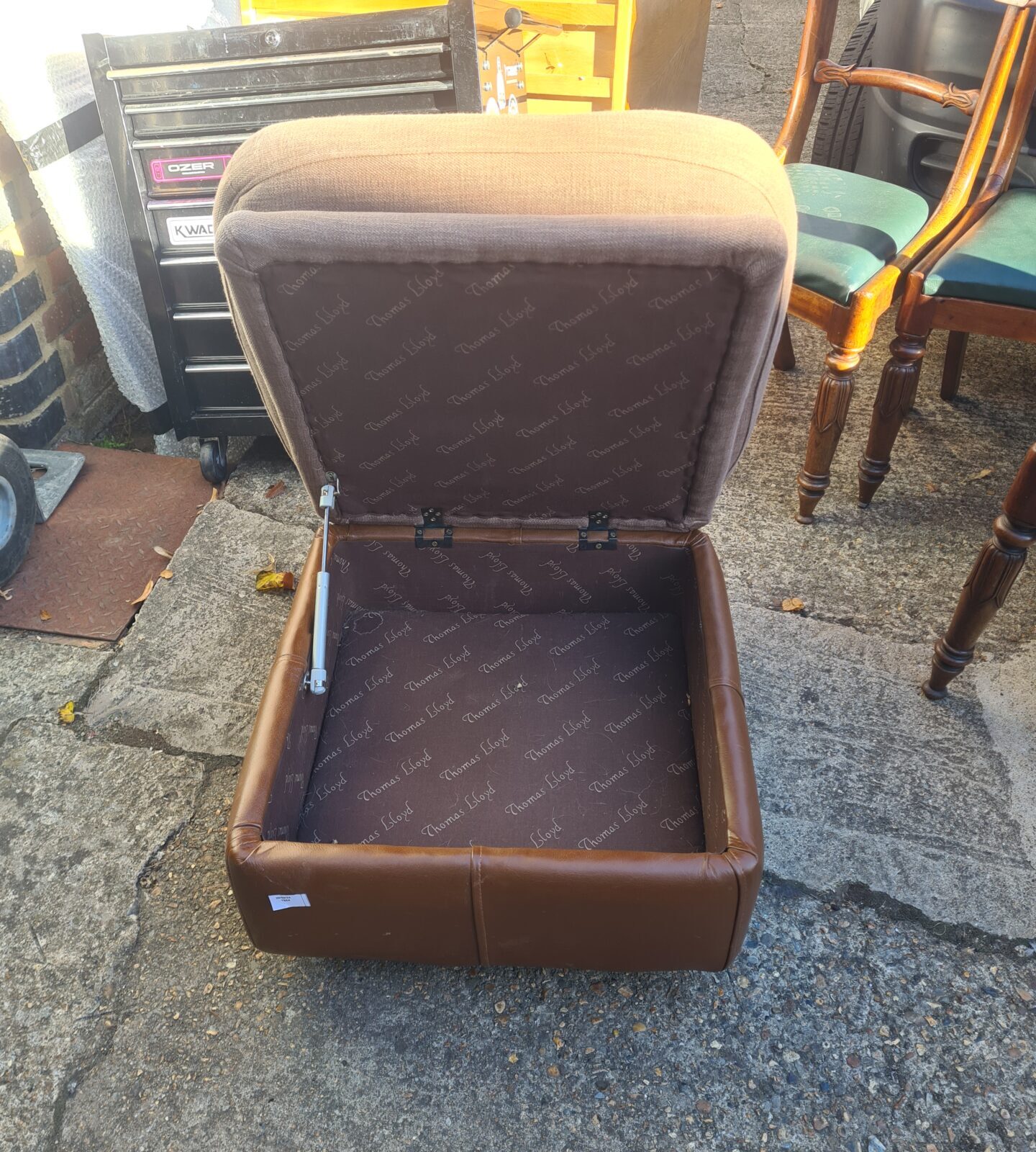Side view of a vintage Thomas Lloyd leather ottoman.