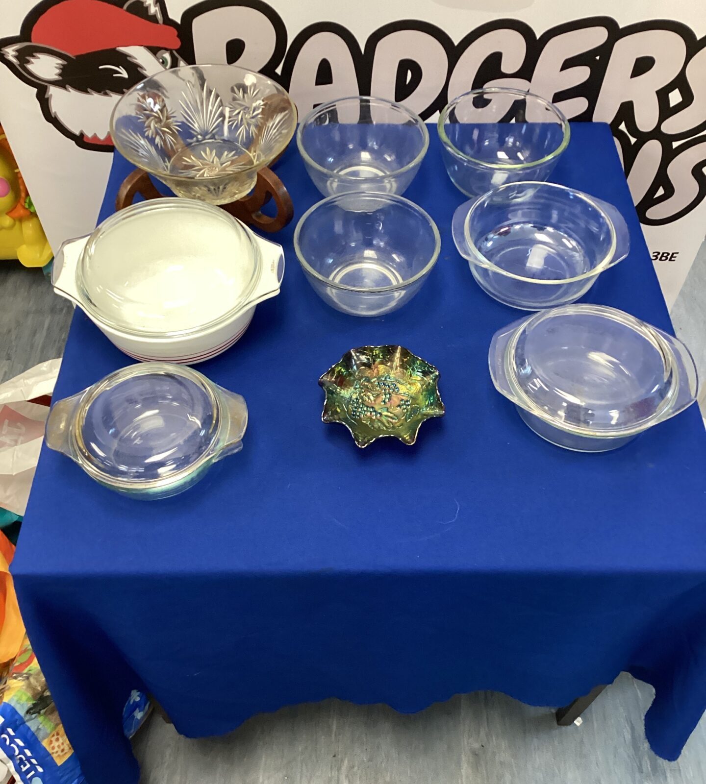 Vintage glassware lot on a blue table, including Pyrex bowls.