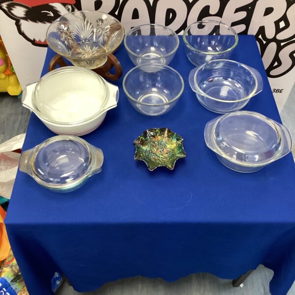 Vintage glassware lot on a blue table, including Pyrex bowls.
