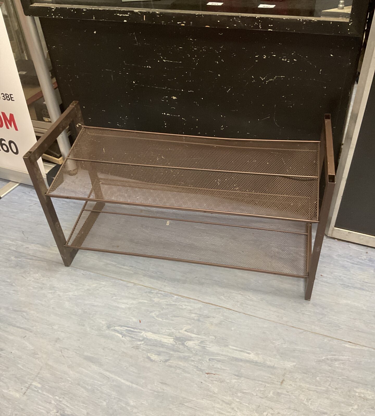Vintage metal shoe rack with three tiers for shoe storage.